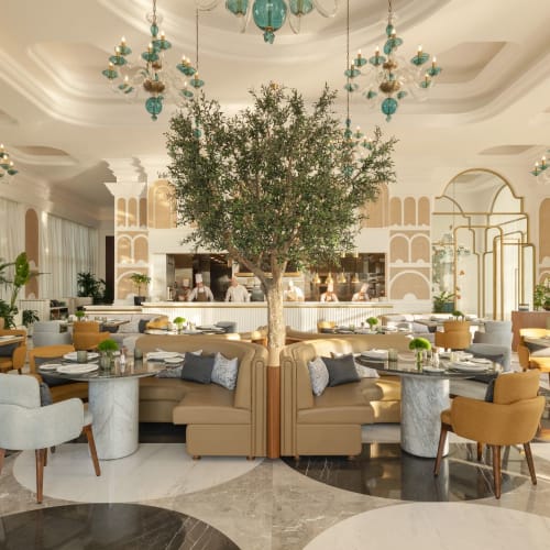 Eine luxuriöse Hotellobby mit einem großen zentralen Baum, umgeben von stilvollen Sitzgelegenheiten und eleganter Beleuchtung.