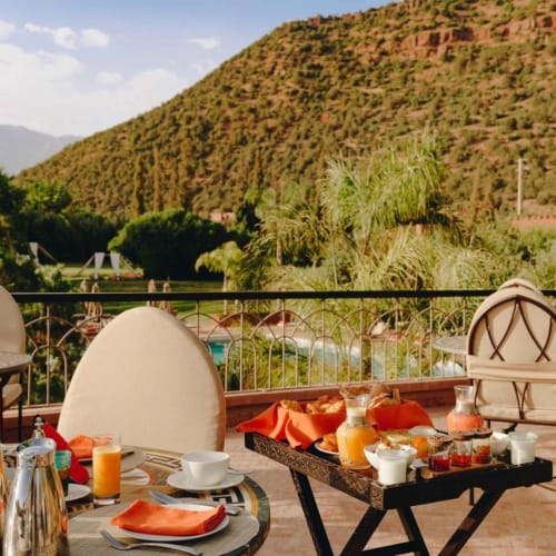 Outdoor terrace dining area with set tables, chairs, and a mountain view in the background.
