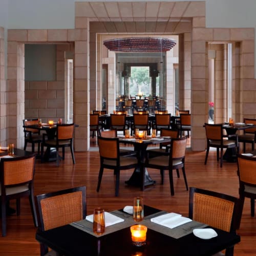 Elegant restaurant with wooden floors, candle-lit tables, and a large chandelier hanging from the ceiling.