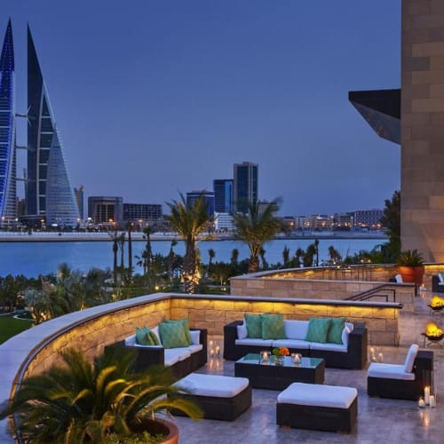 Ein luxuriöser Außenbereich im Four Seasons Hotel Bahrain Bay mit Sitzecken und Blick auf die Stadt skyline und Wasser.
