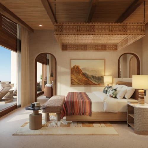 Luxurious bedroom with a view of an outdoor patio and desert landscape, featuring wooden accents and soft lighting.