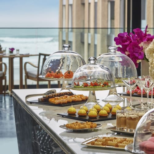 A luxurious dessert buffet with various pastries and cakes on a table by the seaside.