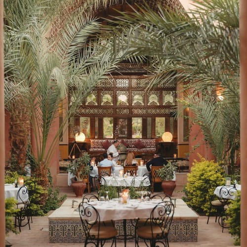 Eleganter Restaurant-Innenhof des Al Moudira Hotels mit üppigen Palmen und traditioneller Dekoration, bereit zum Essen.