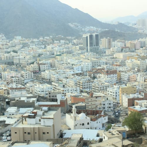 Eine Panoramaansicht der Medina mit dicht gedrängten Gebäuden an den Füßen des Uhud-Gebirges unter einem nebligen Himmel.