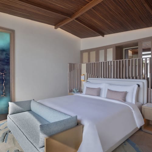 Ein luxuriöses Hotelzimmer mit großem Bett, Nachttischlampen und modernischer Einrichtung in einer geräumigen Suite.