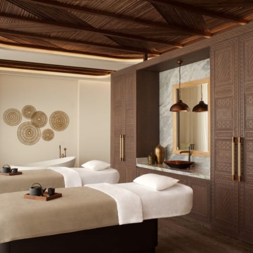 Ein luxuriöser Spa-Bereich mit drei ordentlich gemachten Betten, moderner Dekoration und warmem Licht.