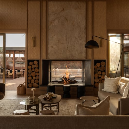 Elegantes Wohnzimmer mit Kamin, moderner Möbel und großen Glastüren, die zur Außenterrasse führen.