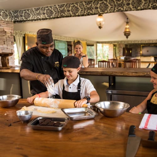 A chef teaching two young children how to bake in a cozy kitchen setting.