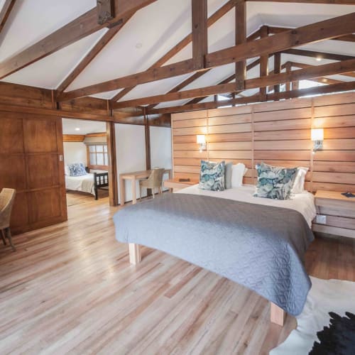 A spacious family suite in a lodge with wooden beams, a large bed with decorative pillows, and a cozy, rustic interior.