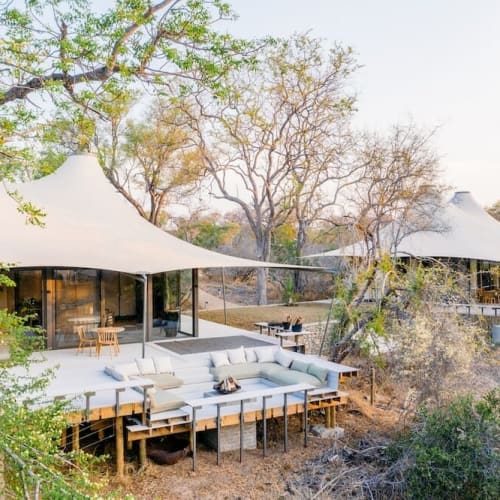 A luxurious tented camp with a spacious outdoor terrace surrounded by trees in South Africa.