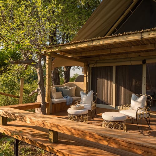 A spacious veranda with cozy seating overlooking green trees and nature in Zimbabwe.