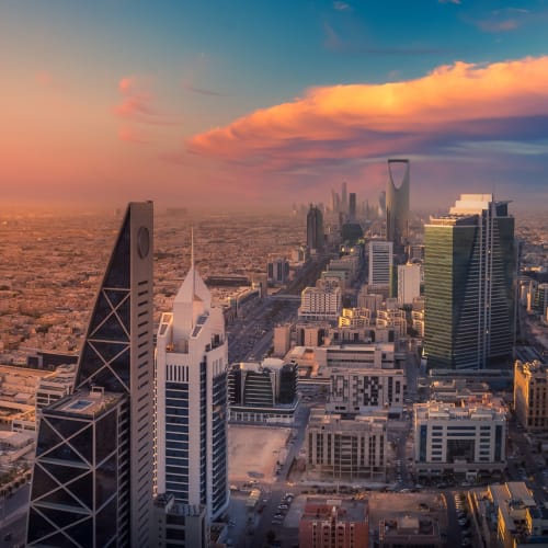 Luftaufnahme der modernen Skyline von Riad bei Sonnenuntergang mit hohen Wolkenkratzern und bunten Wolken.
