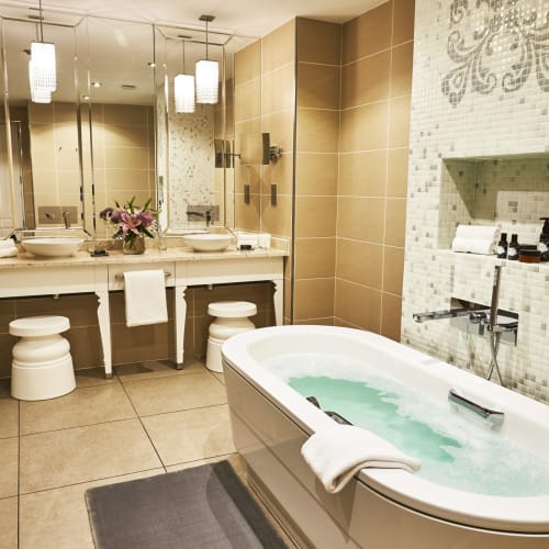 Luxuriöses Badezimmer mit einer großen Badewanne, Doppelwaschbecken mit Spiegeln und eleganter Dekoration in einer Hotelsuite.