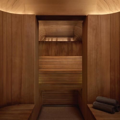 A cozy wooden sauna room with two rolled towels placed on a bench.