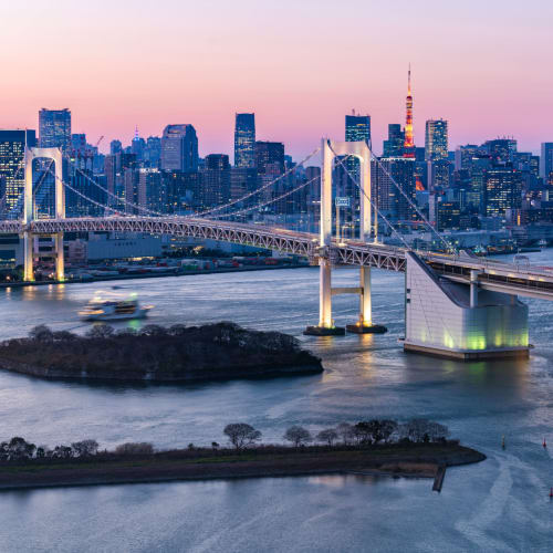 Tokio-Hauptstadt bei Sonnenuntergang mit einer markanten Brücke über den Fluss und Wolkenkratzer im Hintergrund.