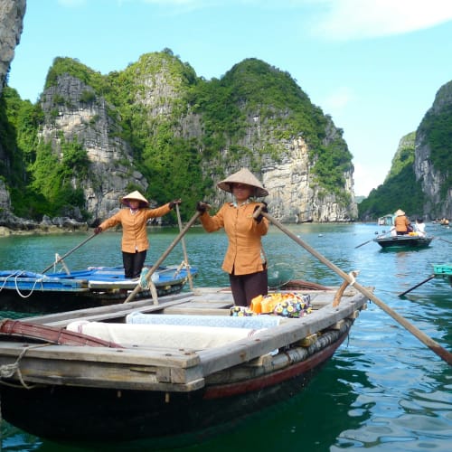 Tourists sailing on traditional boats in a scenic bay with limestone karsts and clear water.