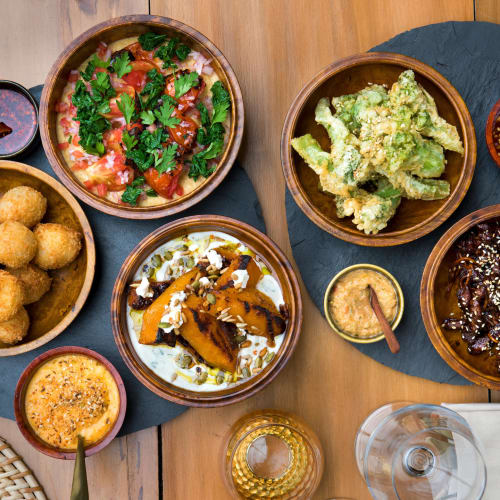 Verschiedene bhutanische Gerichte, serviert auf einem Holztisch, inklusive frittierten Snacks, Gemüsesalat, frittierte Gemüse und verschiedene Saucen.