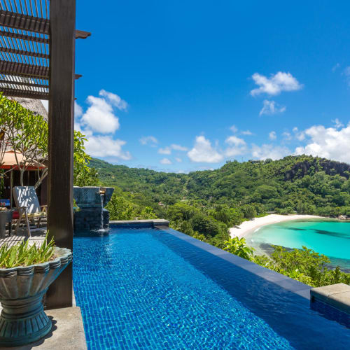 Luxusvilla mit Infinity-Pool mit Blick auf einen tropischen Strand und üppiges Grün auf den Seychellen.
