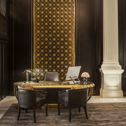 Luxushotel-Rezeption mit dunklen Holztüren, goldener Dekoration und eleganter Ausstattung.