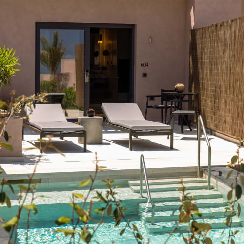 Außenbereich der Echoes Bungalow mit kleinem Zen-Pool mit Treppen, zwei modernen Liegestühlen auf der sonnigen Terrasse und einem Bambus-Sichtschutz neben der Eingangstür.