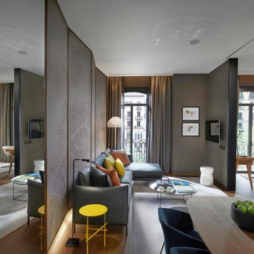 Luxuriöses modernes Wohnzimmer mit bequemen Sitzmöbeln, Dekokissen, großen Fenstern mit Vorhängen und stilvoller Dekoration.
