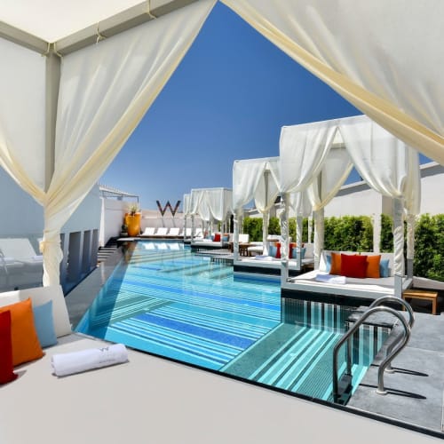 Luxuriöse Dachpool-Anlage mit weißen Kabinen und bequemen Liegestühlen unter klarem blauem Himmel.