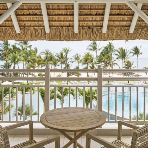 Blick vom Balkon auf einen Pool und tropische Palmen bei einem Resort in Mauritius.