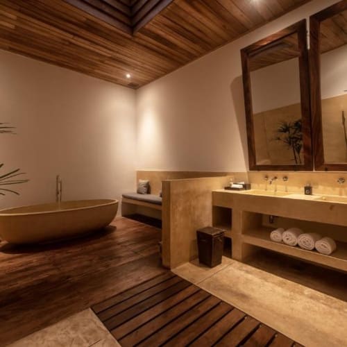 Ein luxuriöses Badezimmer mit einer freistehenden Badewanne, Holzdecke, großen Spiegeln und einer offenen Gestaltung, die eine ruhige Atmosphäre schafft.