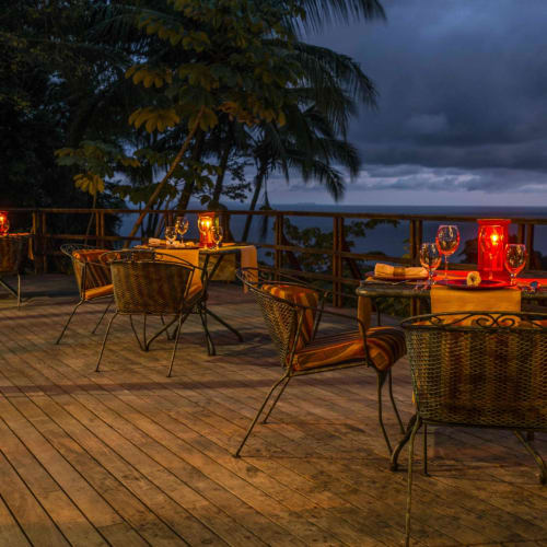 Eine Außenterrasse mit gedecktem Abendessen, beleuchtet von Kerzen und Weingläsern, mit Blick auf eine wunderschöne Landschaft bei Dämmerung.