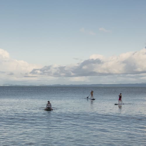 Fünf Personen beim Stand-up-Paddleboarding auf ruhigem Ozeanwasser unter einem teils bewölkten Himmel bei der Lapa Rios Lodge.