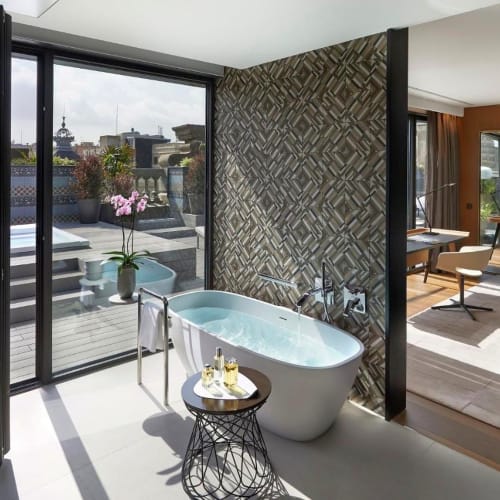 Luxuriöses Badezimmer mit großer Badewanne und privater Terrasse mit Pool, angrenzend an ein modernes Wohnzimmer.