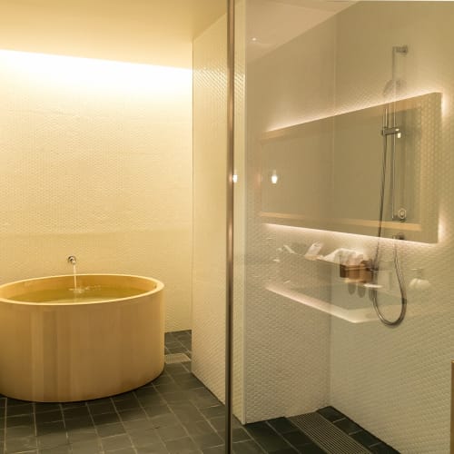 Modernes Hotel-Badezimmer mit einer runden Badewanne und einem Glas-Duschbereich in Kyoto, Japan.