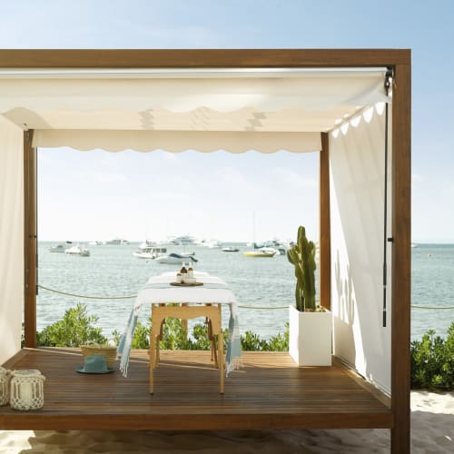 Eine luxuriöse Outdoor-Lodge mit Blick auf das Meer, mit kleinem Tisch, Topfpflanze und entspannter Ausstattung.