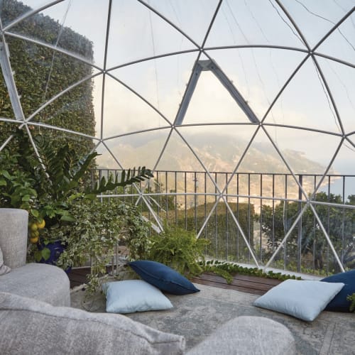 Gemütlicher Indoor-Gartenbereich mit bequemen Sitzmöbeln und Kissen in einem Glastynn, mit Blick auf die Landschaft in Amalfi, Italien.