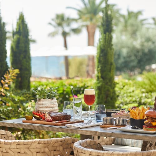 Ein outdoor Esstisch mit Essen und Getränken auf einer sonnigen Terrasse in einem Strandresort.