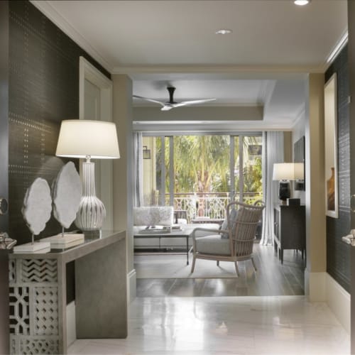 Elegant interior of a grand one-bedroom suite with a view of a bright living area and balcony with greenery.