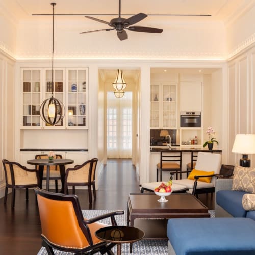 Ein elegantes Wohnzimmer in einer Raffles Singapore Residenz-Suite mit Essbereich, Sitzgelegenheiten und dekorativen Lichtern.