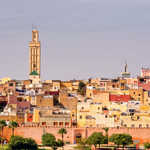 Panoramic view of Meknes city showing colorful buildings and a tall minaret tower.