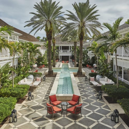 Elegant outdoor courtyard at the Four Seasons Ocean Club with a long pool, palm trees, and seating areas.