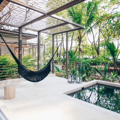 A tranquil outdoor patio area with a hammock, lanterns, and a small pool, surrounded by lush greenery at Nantipa Beach Resort in Costa Rica.