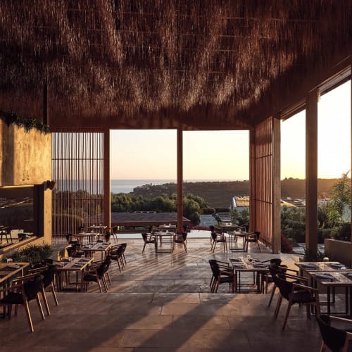 An open-air restaurant with arranged tables and chairs overlooking a sunset view of a coastal landscape in Zakynthos, Greece.