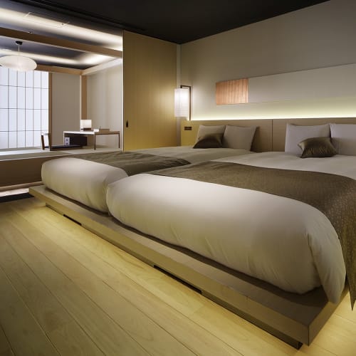 Luxurious hotel room with two large beds, modern decor, and soft lighting in a Japanese style setting.