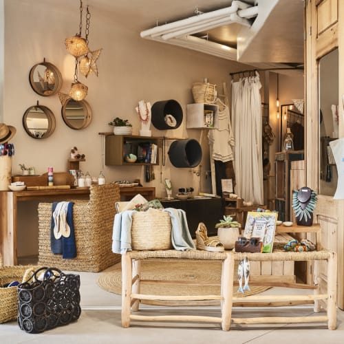 Interior of a boutique at Nobu Hotel Ibiza, decorated with wicker baskets, hats, mirrors, and various accessories, creating a cozy and stylish atmosphere.