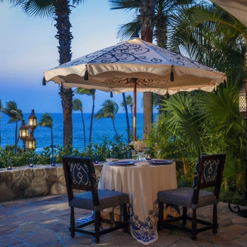 Ein privates Abendessen auf einer Terrasse mit Blick auf den Ozean, umgeben von üppigem Grün und dekorativen Laternen.
