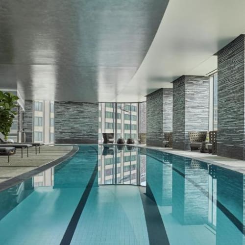 Innenpoolbereich im Four Seasons, Dalton Street, Boston, mit Liegestühlen, großen Fenstern und modernem Dekor.