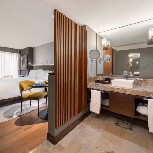 Luxuriöse Hotellounge mit Schlafzimmer und Bad, getrennt durch eine hölzerne Trennwand.