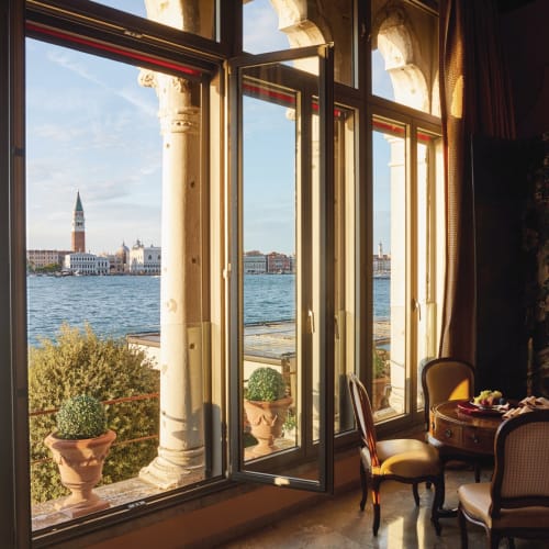 Ein gemütlicher Innenraum der Dogaressa Suite mit Blick auf das Wasser, mit einem Tisch und Stühlen.