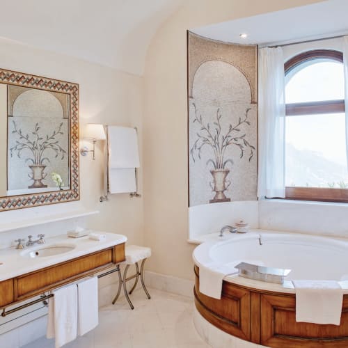Luxurious bathroom with a large bathtub, a decorative mirror, and elegant wall art in a high-end hotel suite.