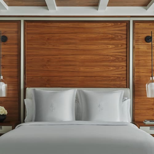 Elegantes Schlafzimmer mit einem Holzkopfteil und modernen Hängeleuchten an jeder Seite.