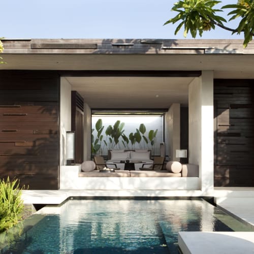 A luxurious one-bedroom villa with an open living area overlooking a private pool, surrounded by lush greenery.